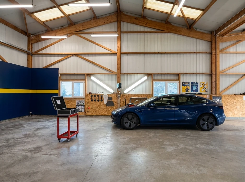 Atelier automobile spacieux avec charpente en bois, sol béton poli