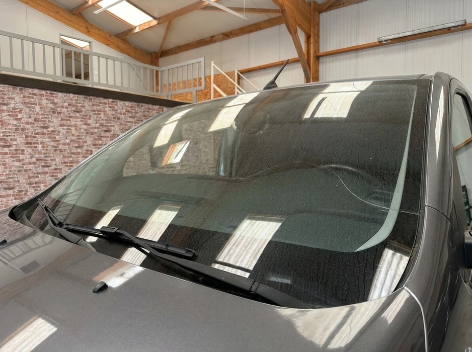 Véhicule gris garé dans un garage industriel avec mezzanine en bois et murs en briques