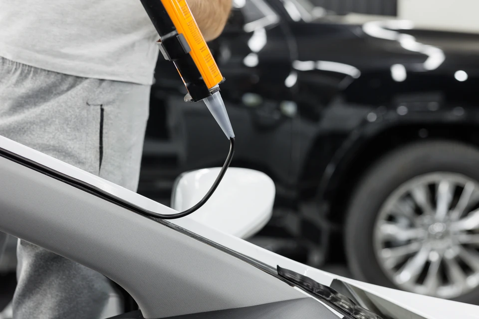 Extérieur ensoleillé, technicien professionnel effectue la réparation d'un pare-brise automobile