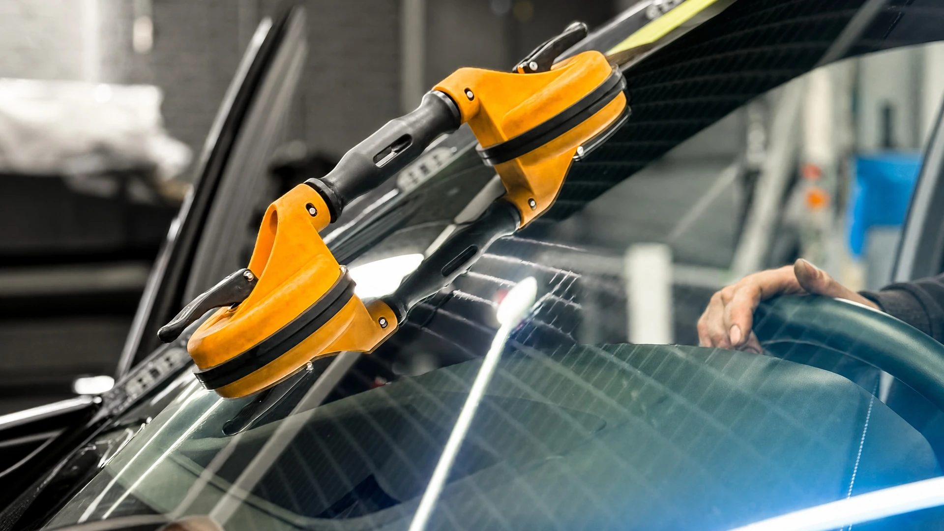 Extérieur automobile, technicien avec gants nitrile bleus effectuant remplacement pare-brise