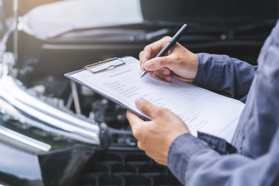 Technicien automobile installant un pare-brise sur véhicule noir dans garage professionnel