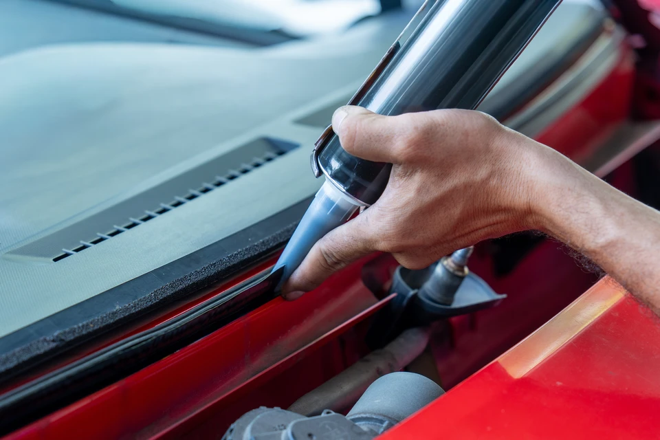 Deux techniciens effectuent la réparation d'un pare-brise automobile en extérieur