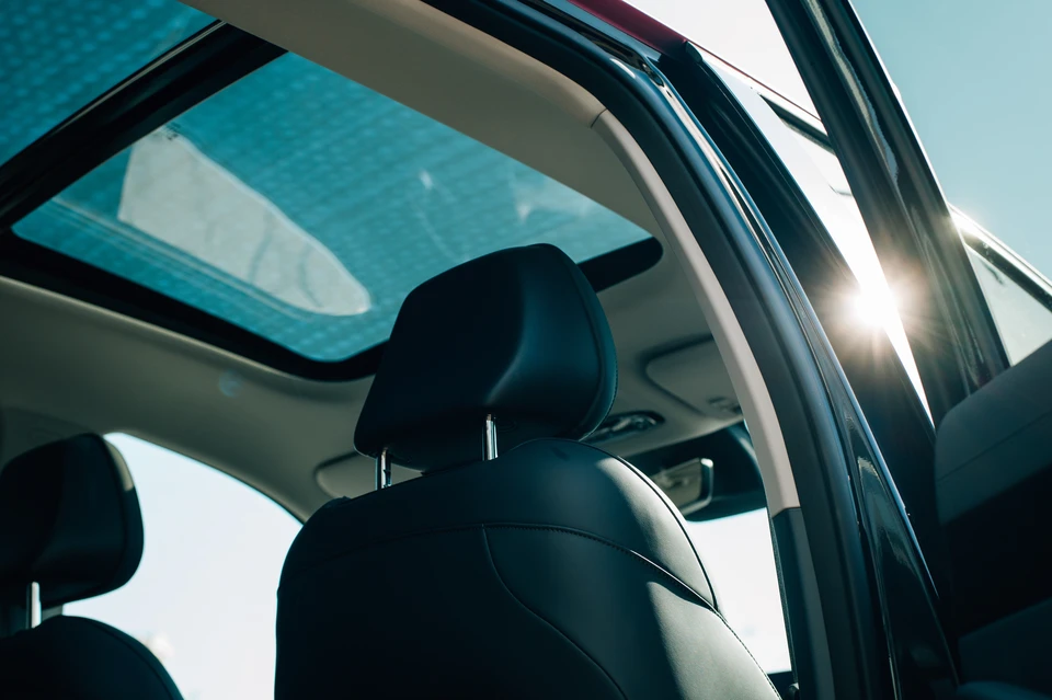 Deux techniciens en combinaison de travail bleue installent un pare-brise automobile dans un atelier de réparation vitré
