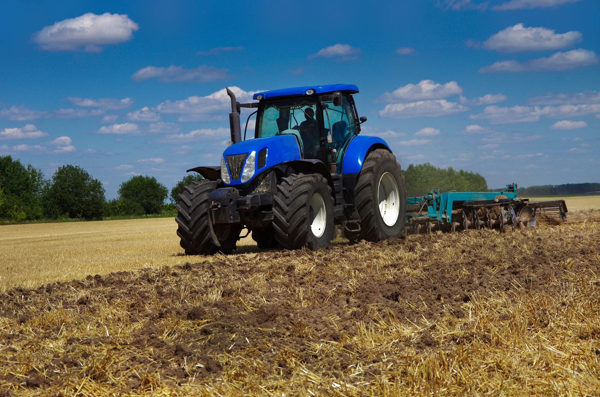 Tracteur agricole circulant entre les rangées de vignes en automne, feuillage doré et rougeâtre, travaux viticoles de fin de saison